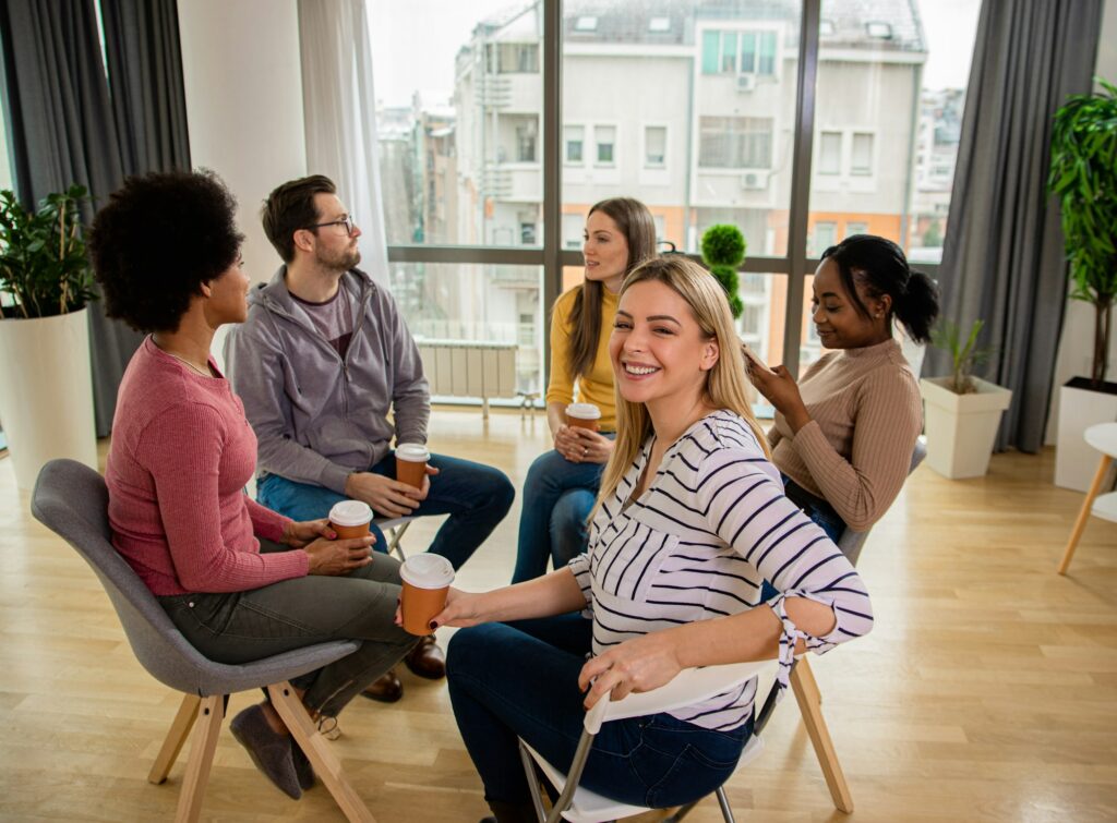 Diverse group of people sitting in circle in group therapy session.