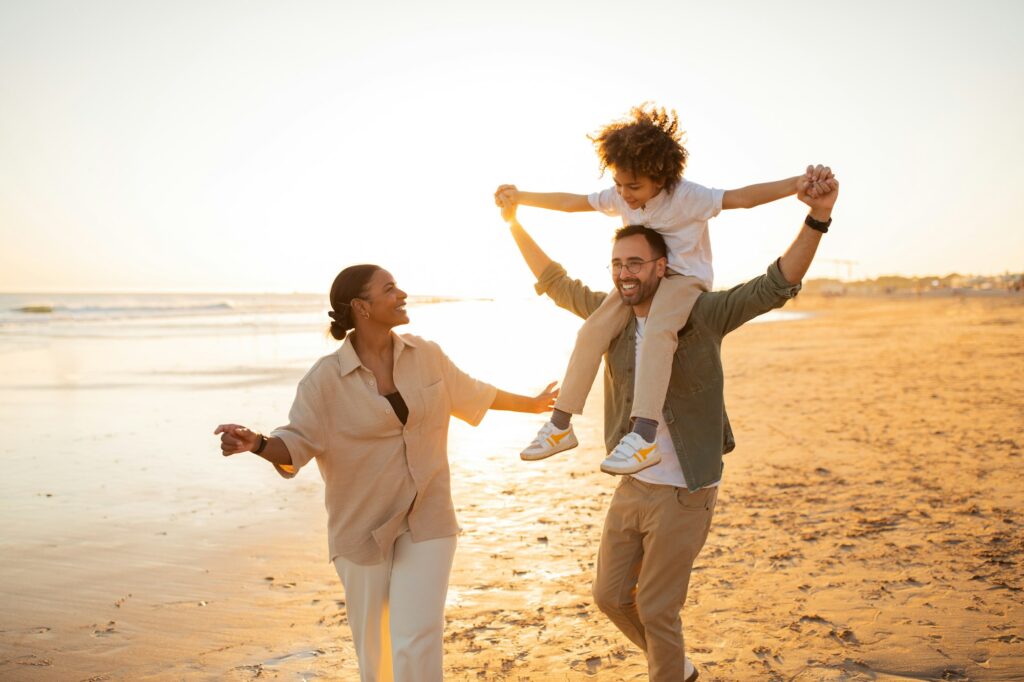 Joyful family beach day. Happy family having fun, father carrying son on shoulders and walking